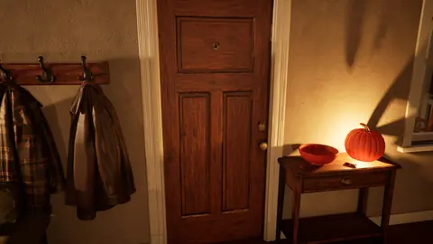 The closed front door from inside, with coats on hooks and a lit pumpkin on the entry table